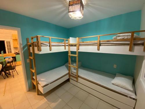 a room with three bunk beds in a house at Linda casa em condomínio Sun House Maresias com piscina - 50 m da praia in Maresias