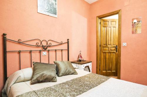 a bedroom with a bed in a room with pink walls at El Robledillo in Robledillo