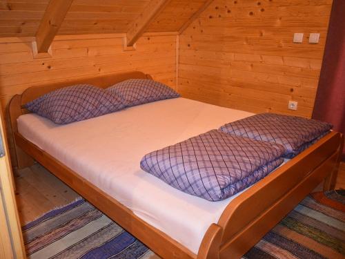 a bed in a cabin with two pillows on it at Cottage on the Rama lake in Jaklići