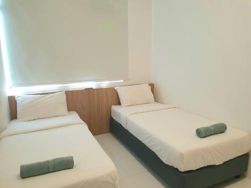 2 Betten in einem kleinen Zimmer mit weißer Bettwäsche in der Unterkunft MY AZ SWEET HOMESTAY in Alor Setar