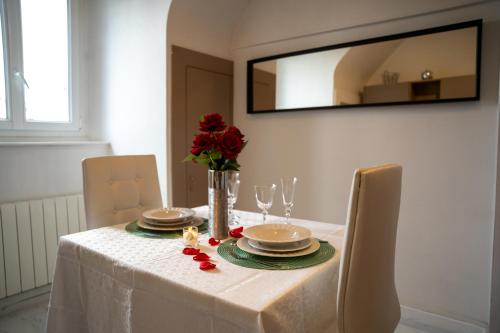 une table avec un tissu de table blanc et un vase avec des roses rouges dans l'établissement Charmant studio à quelques pas du centre-ville, à Troyes