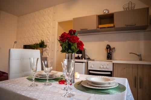 a table with two plates and a vase with red roses at Charmant studio à quelques pas du centre-ville in Troyes