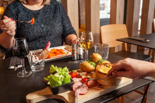 a woman sitting at a table with a plate of food at Ibis Pontarlier in Pontarlier