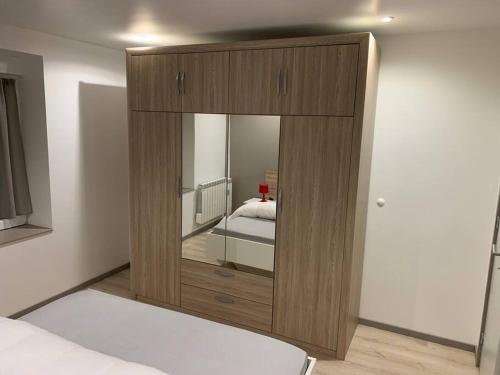 a bedroom with a large wooden cabinet with a mirror at Appartement neuf, au coeur du massif Vosgien in Fraize