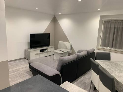 a living room with a couch and a flat screen tv at Appartement neuf, au coeur du massif Vosgien in Fraize