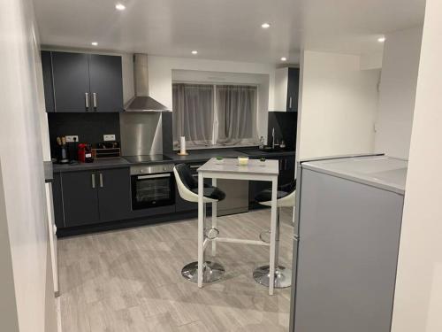 a kitchen with black cabinets and a white table and chairs at Appartement neuf, au coeur du massif Vosgien in Fraize