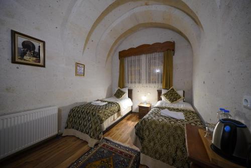 Habitación con 2 camas, mesa y ventana en Arch Palace, en Göreme