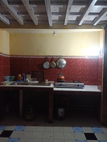 a kitchen with red tiled walls and a counter top at Kumojoyo Homestay in Borobudur