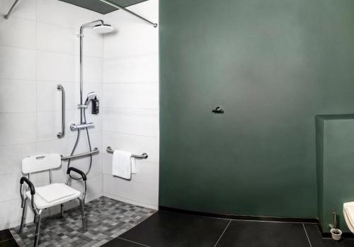 a bathroom with a shower and a chair in it at Ibis Pontarlier in Pontarlier