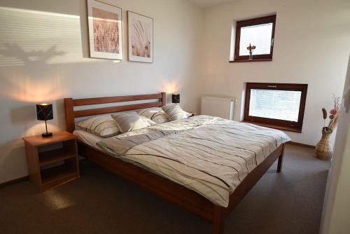 a bedroom with a large bed with a night stand and a lamp at Apartmán DOKY Lipno in Lipno nad Vltavou