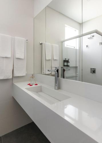a white bathroom with two sinks and a mirror at Pousada Gaúcha in Bombinhas