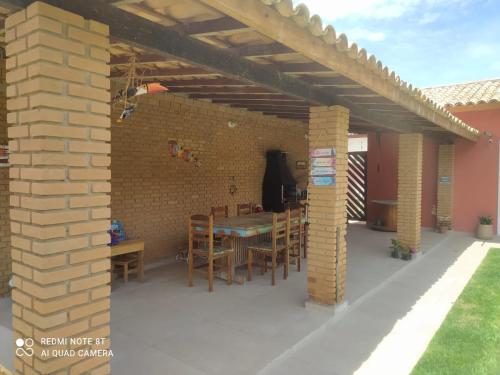 eine Terrasse mit einem Tisch, Stühlen und einer Ziegelwand in der Unterkunft Cantinho de Barê in Barequeçaba