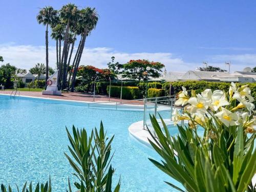 a swimming pool with blue water and flowers at cozy & modern bungalow w/private garden bbq+wifi in Maspalomas