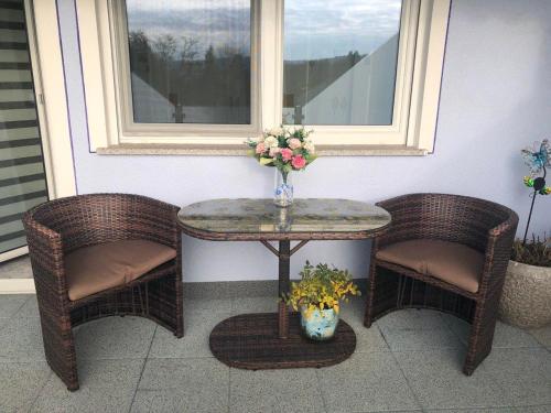 a table with two chairs and a table with a vase of flowers at Berta in Neunkirchen