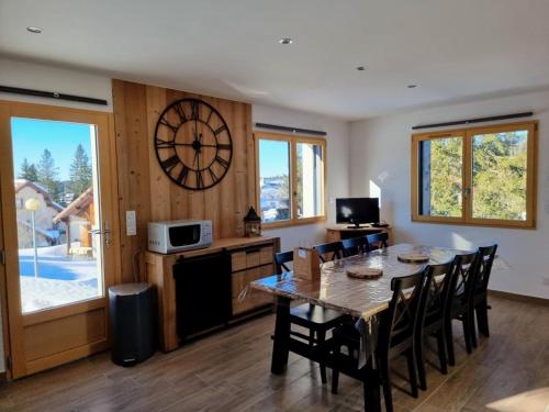 a dining room with a table and a clock on the wall at Chalet de charme avec terrasse, jardin et sauna extérieur in Chapelle-des-Bois