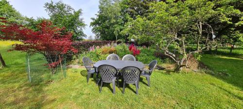 a table and chairs in a yard with flowers at Les Randonneurs - Maison spacieuse avec jardin in Malmedy
