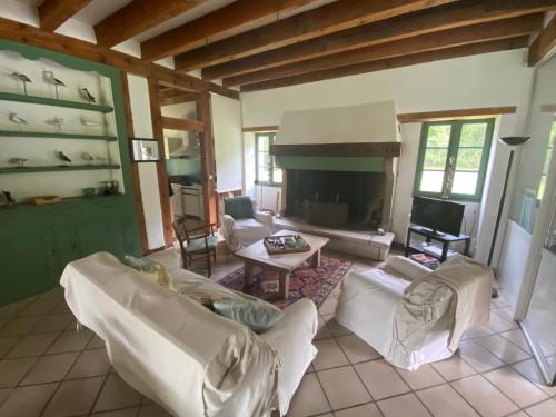 Elle comprend un salon doté d'un mobilier blanc et d'une cheminée. dans l'établissement Domaine de Montourley, à Castets