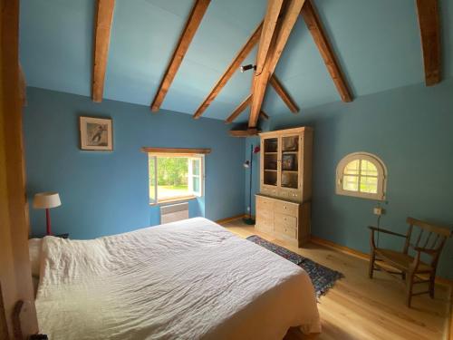 um quarto com paredes azuis e uma cama e uma cadeira em Domaine de Montourley em Castets