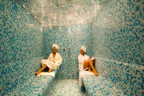 two people sitting in a room with blue tiles at Relais La Colombara Spa & Wellness in Travo