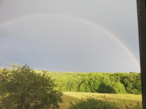 a rainbow in the sky over a field at Au petit bois magique in Payrac