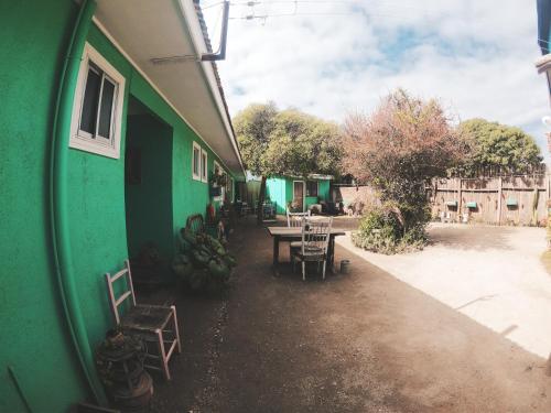 a green building with tables and chairs outside of it at Los Rukos Cabanas (Bungalows) in Pichilemu