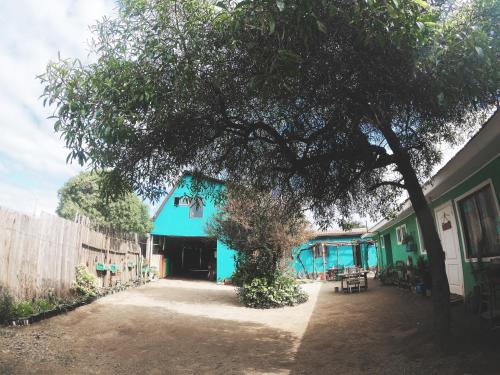 a blue building with a tree in front of it at Los Rukos Cabanas (Bungalows) in Pichilemu
