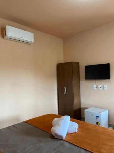 a bedroom with a bed with a tv and a cabinet at Chalés Cantin da Serra - Serra da Canastra/MG in São Roque de Minas