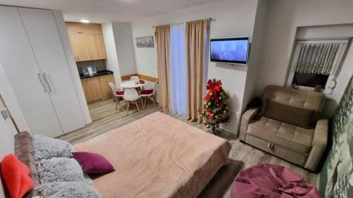 a living room with a couch and a table with a christmas tree at Snowman Studio Apartment Jahorina in Jahorina