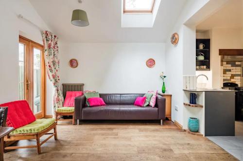 ロンドンにあるLovely Three Bedroomed House, Parking 2 Carsのリビングルーム(グレーのソファ、ピンクの枕付)