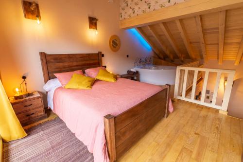 a bedroom with a bed with pink sheets and yellow pillows at La Galiana loft nature in Casarejos