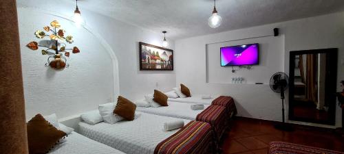 a room with two beds and a tv on the wall at Hotel Real Antigua in Antigua Guatemala