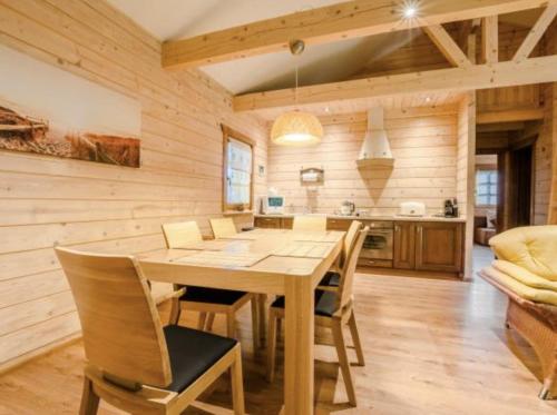 a kitchen and dining room with a wooden table and chairs at Klimatyczny domek z drewna nad morzem in Dębina