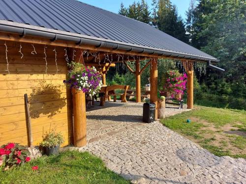 a wooden pavilion with flowers in a garden at Sielankowo-dom na wyłączność in Istebna