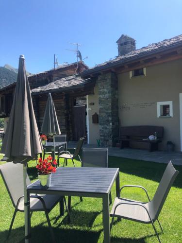 a patio with a table and chairs and an umbrella at L'Abreny in Brusson