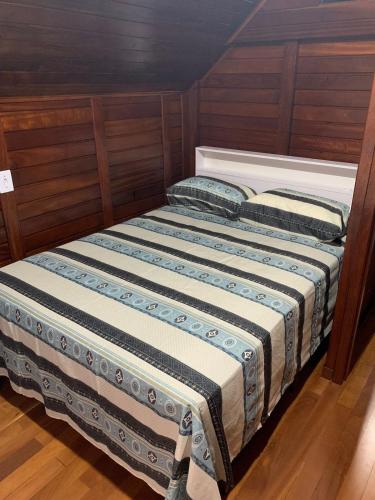a bed in a room with wooden walls at Chalés Vô João in Penha