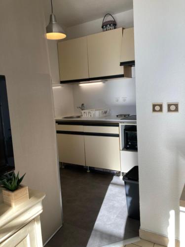 uma cozinha com armários brancos e um forno com placa de fogão em T2 Classé 2* calme au coeur du village provençale em Gréoux-les-Bains
