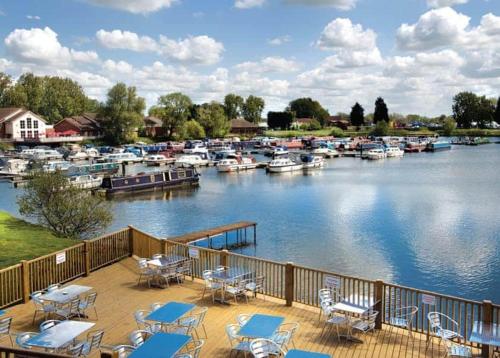 a deck with tables and chairs next to a marina at Lovely Static 8 Bed Caravanat at Billing Aquadrome in Great Billing