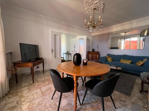 een woonkamer met een tafel en een blauwe bank bij Appartement climatisé F3 proche plage port et aéroport in Ajaccio