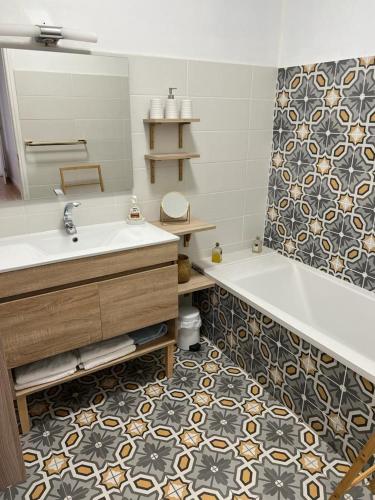 a bathroom with a tub and a sink and a mirror at Appartement climatisé F3 proche plage port et aéroport in Ajaccio