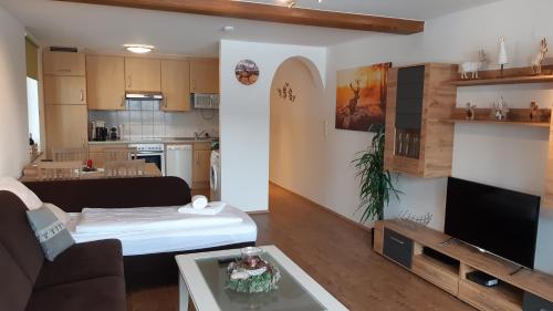 un salon avec un canapé et une télévision et une cuisine dans l'établissement Apartment Romy, à Kaprun