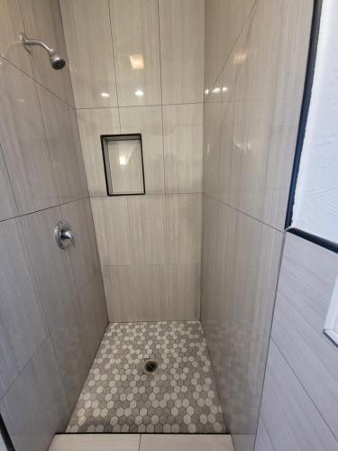 a shower with a glass door and a tile floor at Townhouse Motel in Bishop