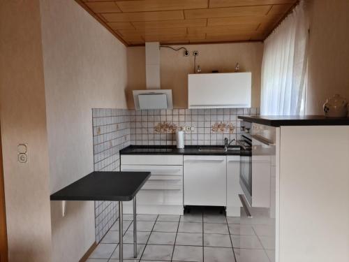 a kitchen with white cabinets and a black counter top at Ferienwohnung Cornelia und Michael Persang GbR in Eppenbrunn