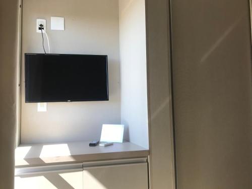 a room with a television and a table with a laptop at Hotel Morada Del Este in Canoas
