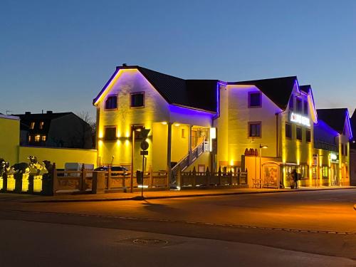 a white building with purple lights on a street at Mr.Liao Hotel in Himberg