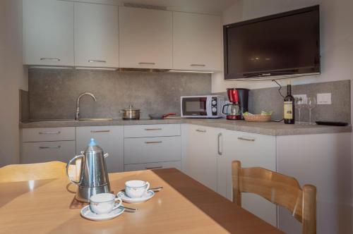 a kitchen with white cabinets and a wooden table at Apartments UDERA in Selva di Val Gardena