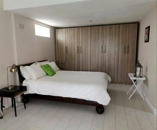 Manz' amahle Guest Cottage في هارتبيسبورت: غرفة نوم مع سرير أبيض كبير ودواليب خشبية