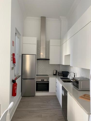 a kitchen with white cabinets and a stainless steel refrigerator at Casa Cubista in Olhão
