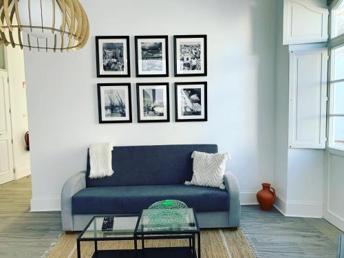 a blue couch in a living room with pictures on the wall at Casa Cubista in Olhão