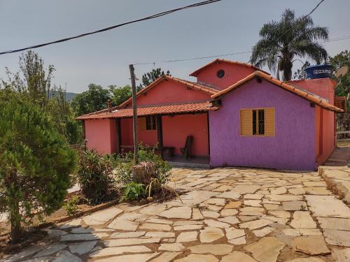 una pequeña casa con pintura morada y rosa en Recanto da Serra, en São Thomé das Letras