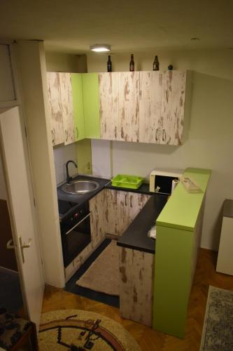 een keuken met groene en witte kasten en een wastafel bij 3pko City center apartment in Banja Luka